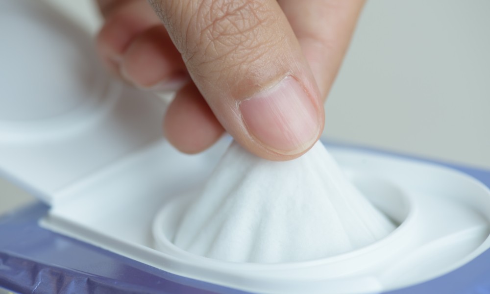 what to pack in your carry-on: Closeup woman hand holding wet wipes from package.