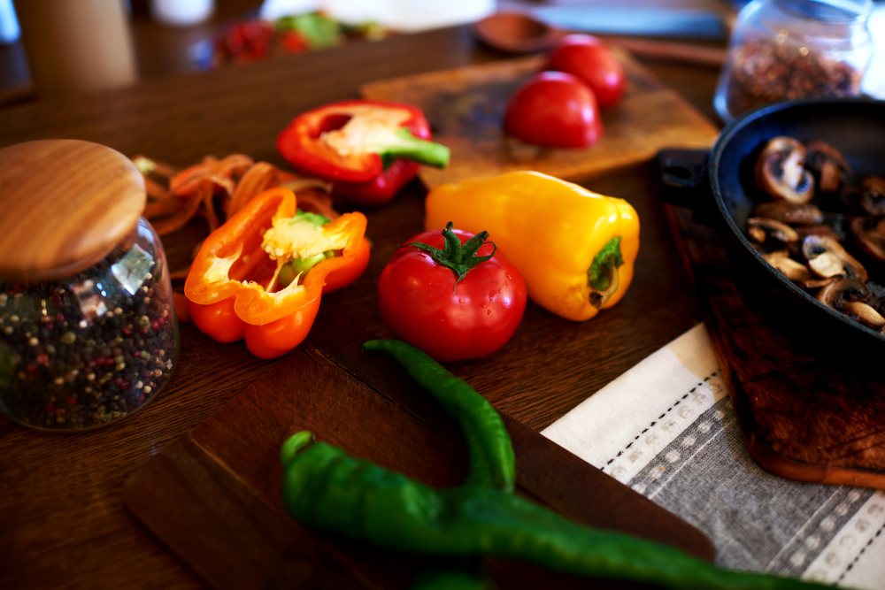 In the kitchen, vegetarian restaurant chef chopped pepper and tomatoes mushrooms are already close to the pan fried