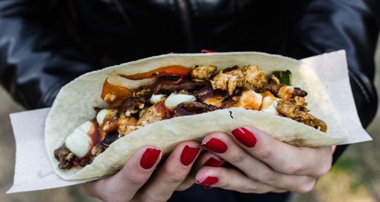 Close up photo of a traditional Mexican taco with beef filling at a street food market. Selective focus.