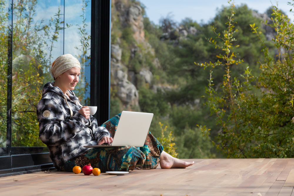 Woman sitting on the floor drinking coffee while on laptop