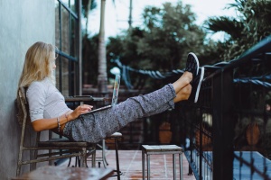 beautiful girl in a relaxed position working at a laptop in a cafe . Freelancing on vacation . Working in co-working in a cafe in the open air .