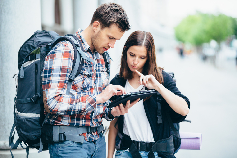 Couple of backpackers looking at city map on tablet computer