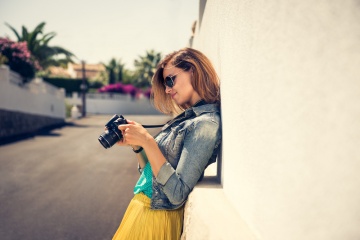 Portrait of a young, fit and attractive woman taking a photo outdoor. Posing on the street on a sunny summer day. Girl looking at the camera.