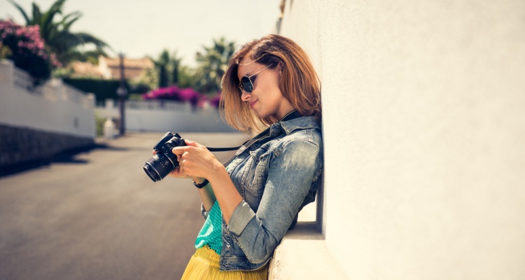 Portrait of a young, fit and attractive woman taking a photo outdoor. Posing on the street on a sunny summer day. Girl looking at the camera.