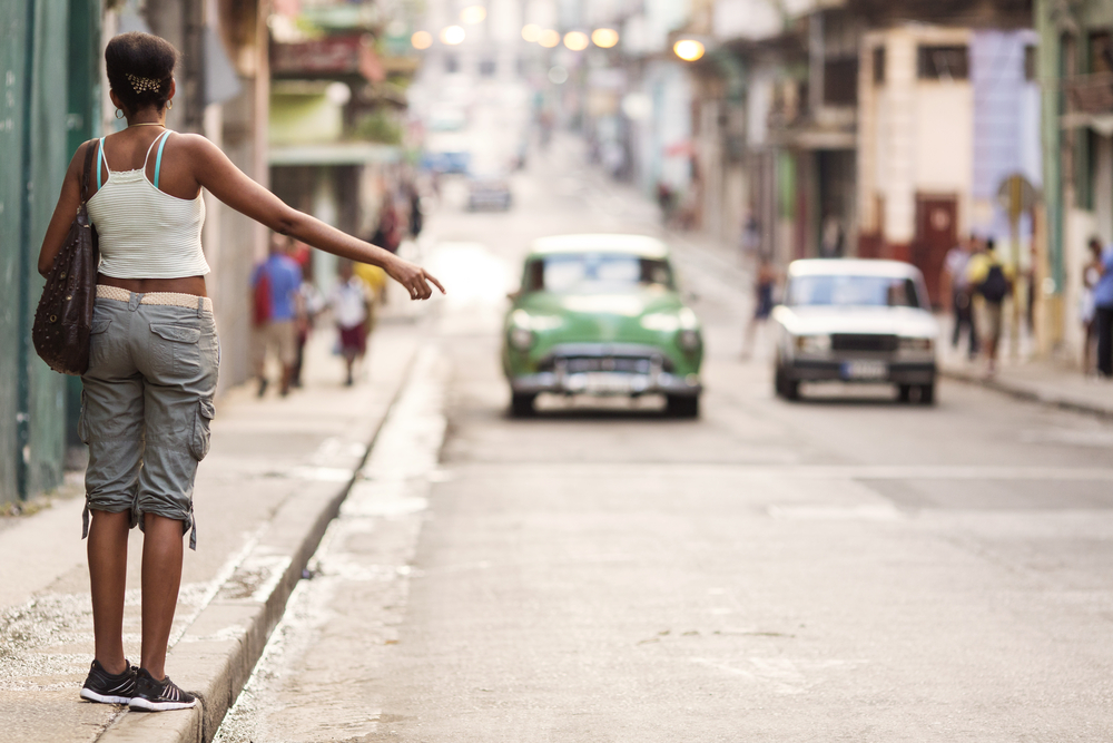 Young professional woman hitching a taxi in Havana, Cuba