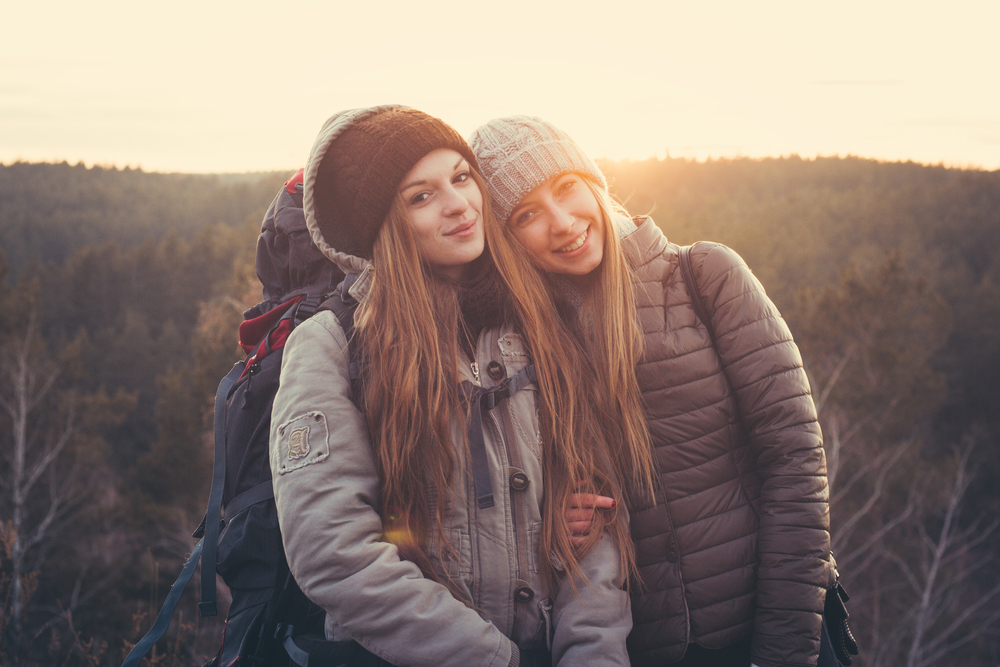 Lifestyle portrait of young traveler best friends girls at sunset, fun and smile