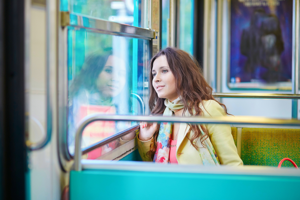 Beautiful young woman travelling in a train of Parisian subway and looking through the window