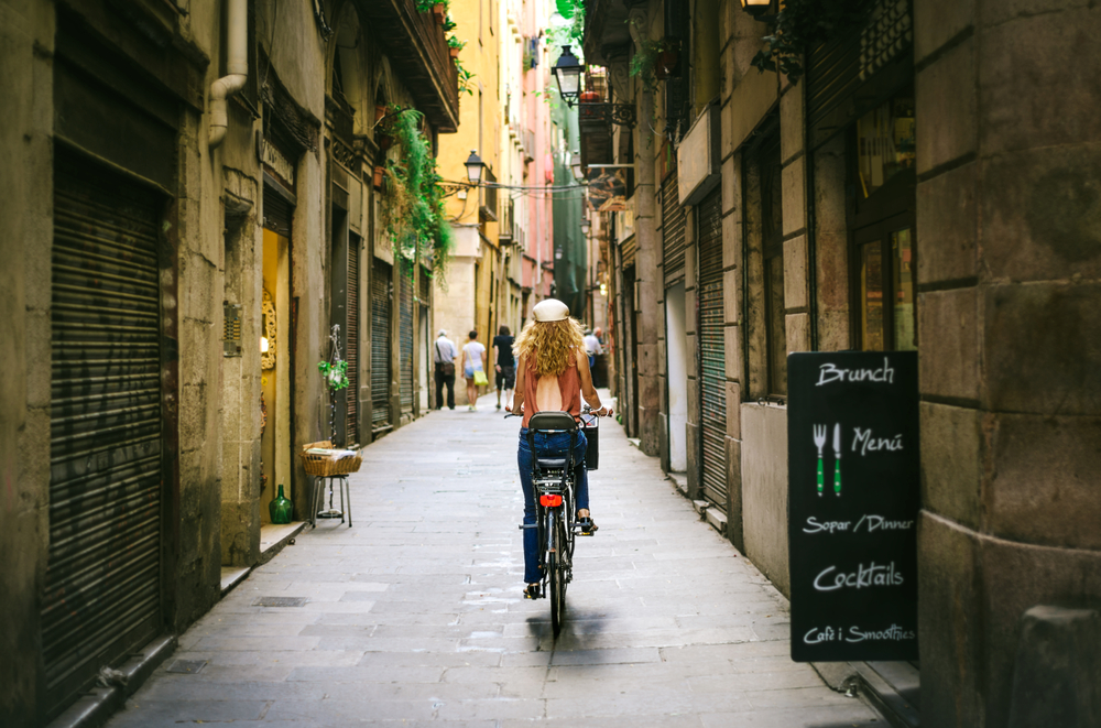 Woman riding bicycle through old street of Barcelona