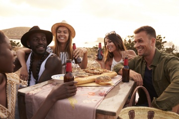 Group Of Friends Enjoying Picnic On Cliffs By Sea