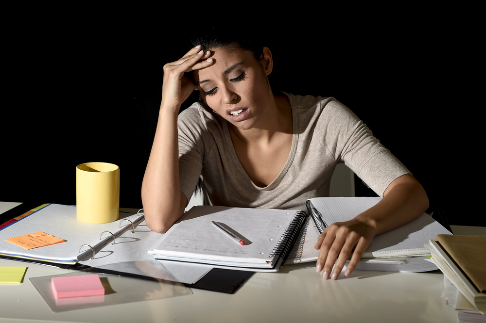 young beautiful Spanish girl studying tired and bored at home late night looking sad and stressed preparing exam in overwhelmed and frustrated face expression in education stress concept