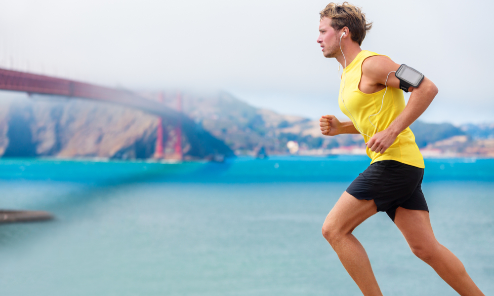 Sporty fit young jogger jogging by San Francisco Bay and Golden Gate Bridge.