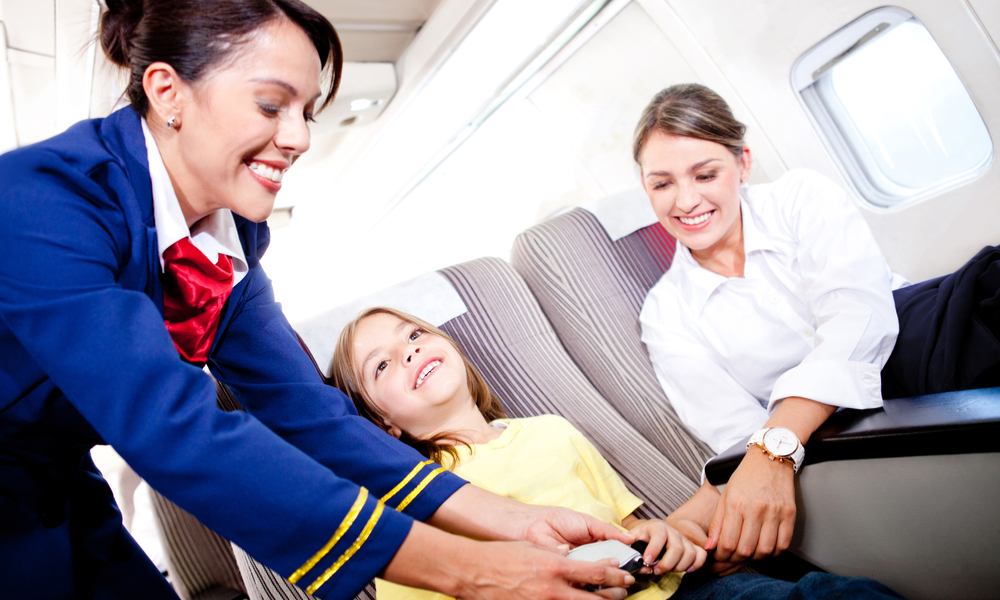 Flight attendant fastening seat belt to boy for a safe trip