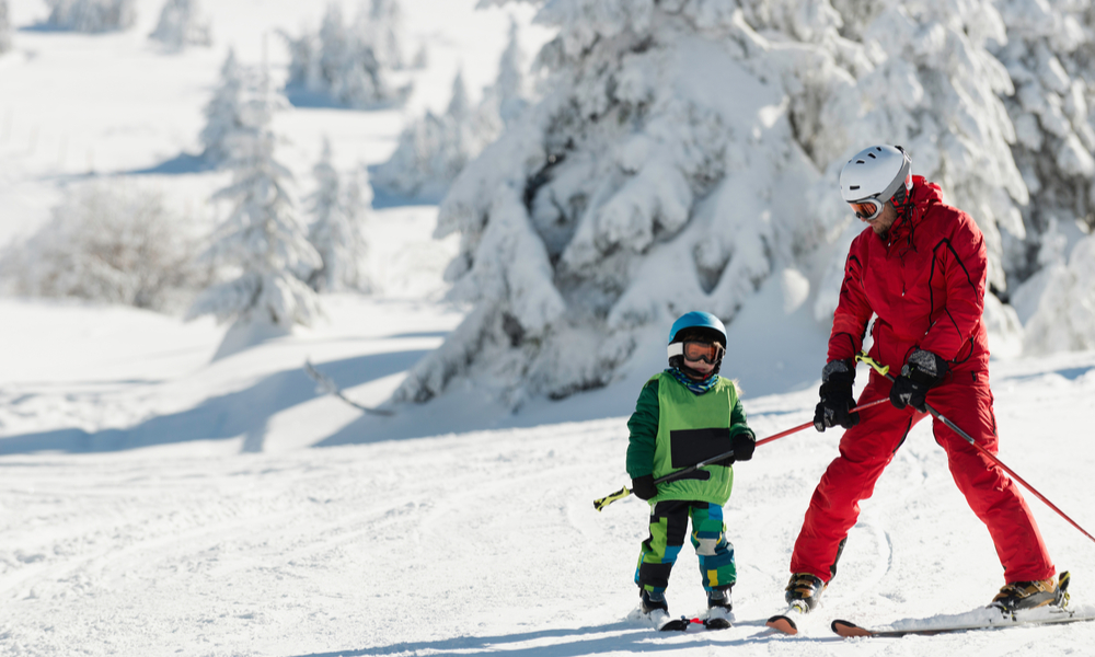 Little boy learning to ski with instructor