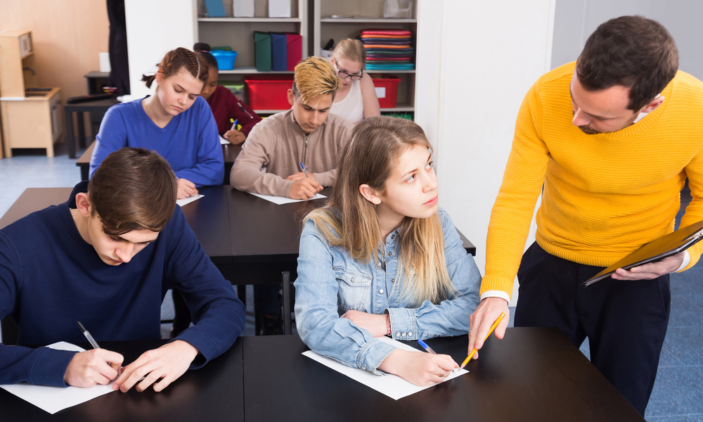 positive english male teacher clearing up complicated issue to pupil during exam in class