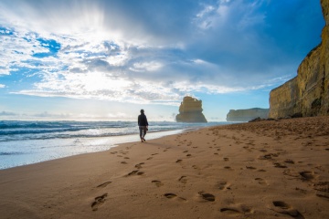 Lonely man walking on the beach leaving footprints