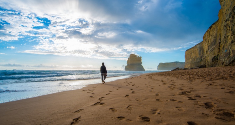 Lonely man walking on the beach leaving footprints