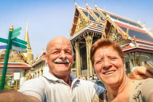 Senior happy couple taking a selfie at Grand Palace temples in Bangkok - Thailand