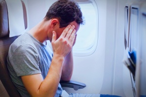 passenger holding his head on flight