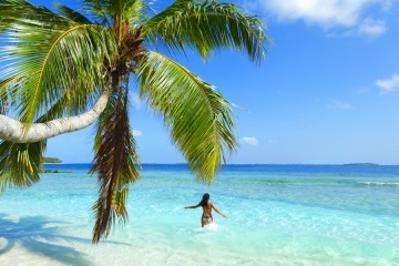 Woman splashing in sea near beautiful beach with palm