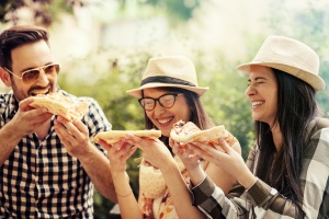 Group of young people having fun in the park and eating pizza.