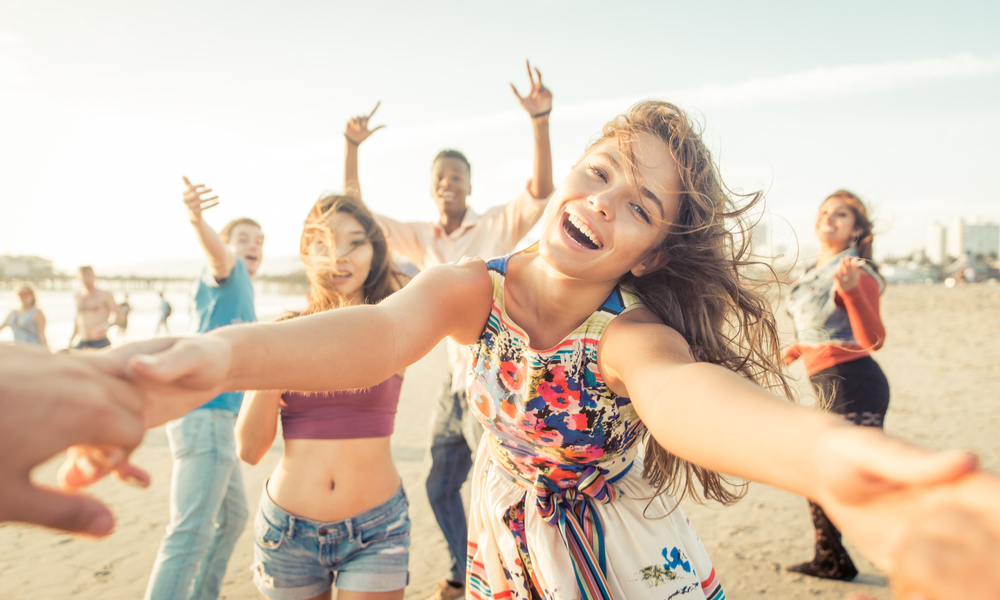 Group of friends having fun and dancing on the beach.