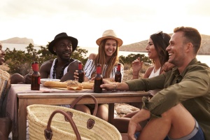 Group Of Friends Enjoying Picnic On Cliffs By Sea