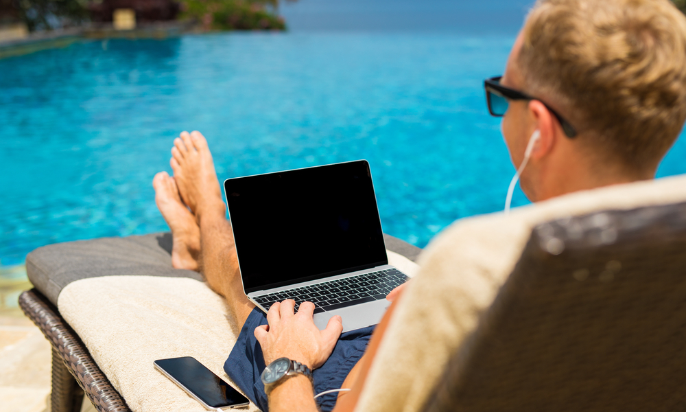 Man chilling by the pool and using laptop computer