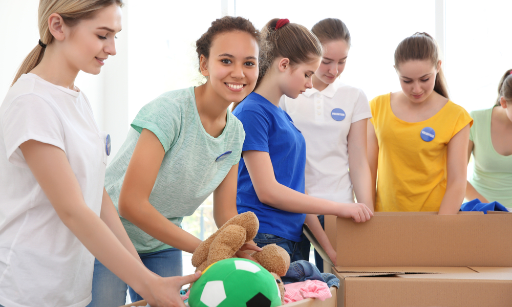 Young volunteers with boxes of donations indoors