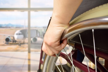 rear view of a man in wheelchair at the airport with focus on hand