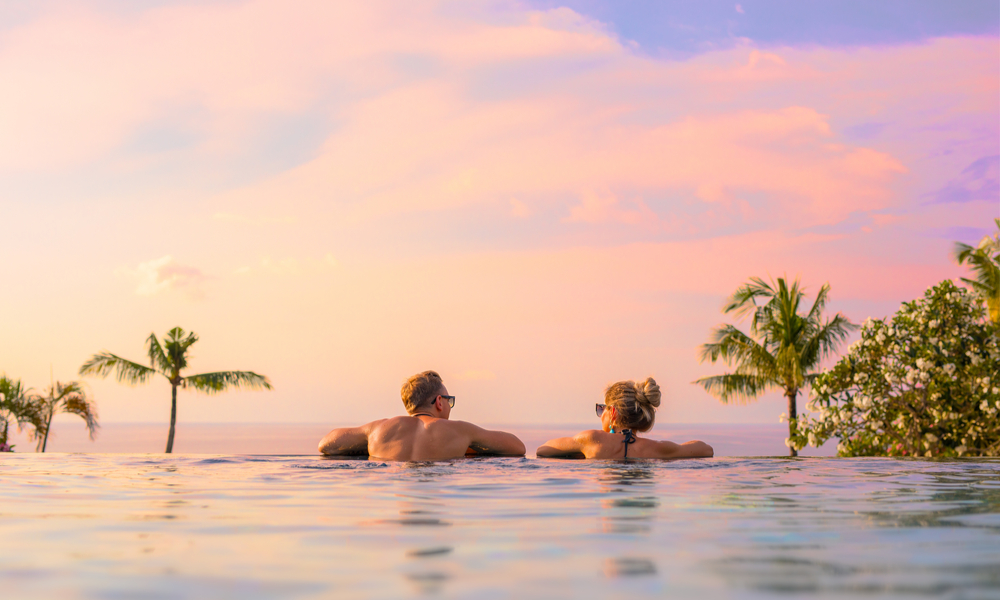 Romantic couple looking at beautiful sunset in luxury infinity pool in Bali