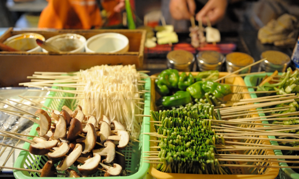 Street restaurant in China, Shanghai. People preparing vegetable skewers. 