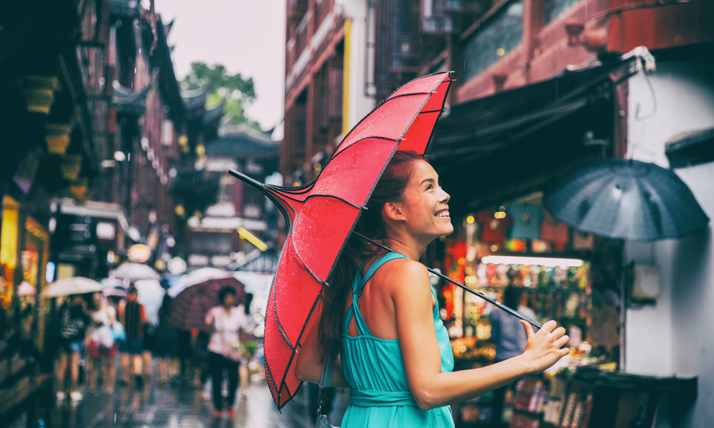 Rainy day girl tourist under red oriental umbrella in back alleys in Shanghai, China.