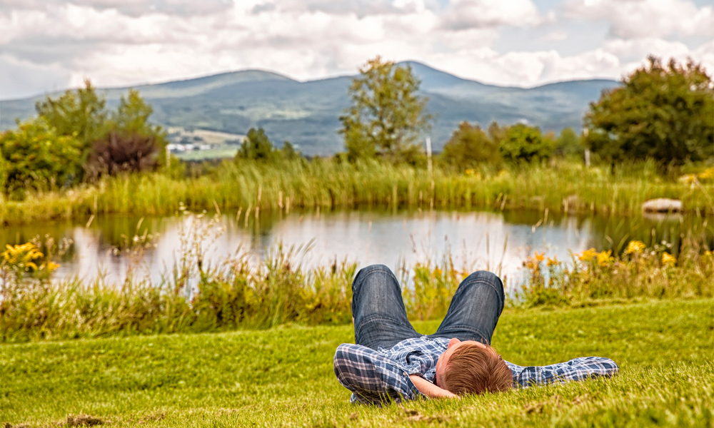 man relaxing near a river in Vermont