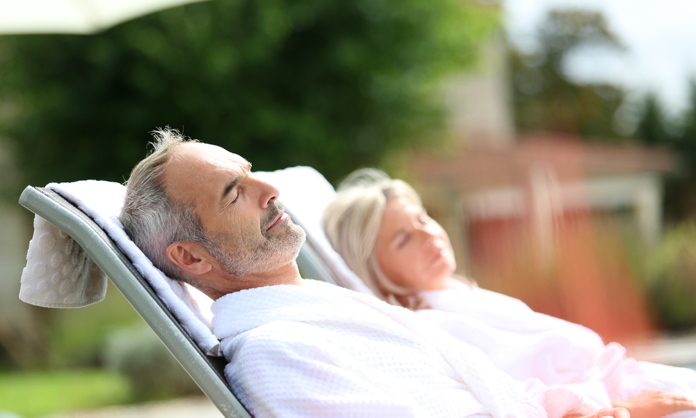 Senior couple in spa hotel relaxing in long chairs