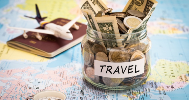 Travel budget concept. Travel money savings in a glass jar with compass, passport and aircraft toy on world map