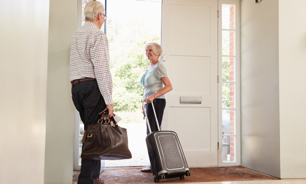 Senior couple with luggage leaving home for a holiday