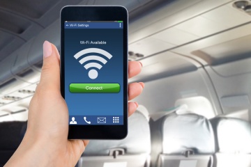 Close-up Of Person's Hand Holding Mobile Phone Showing WiFi Connection In Airplane