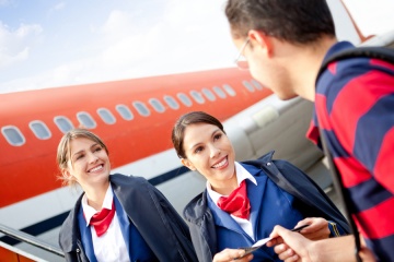 Friendly flight attendants welcoming passenger into the airplane