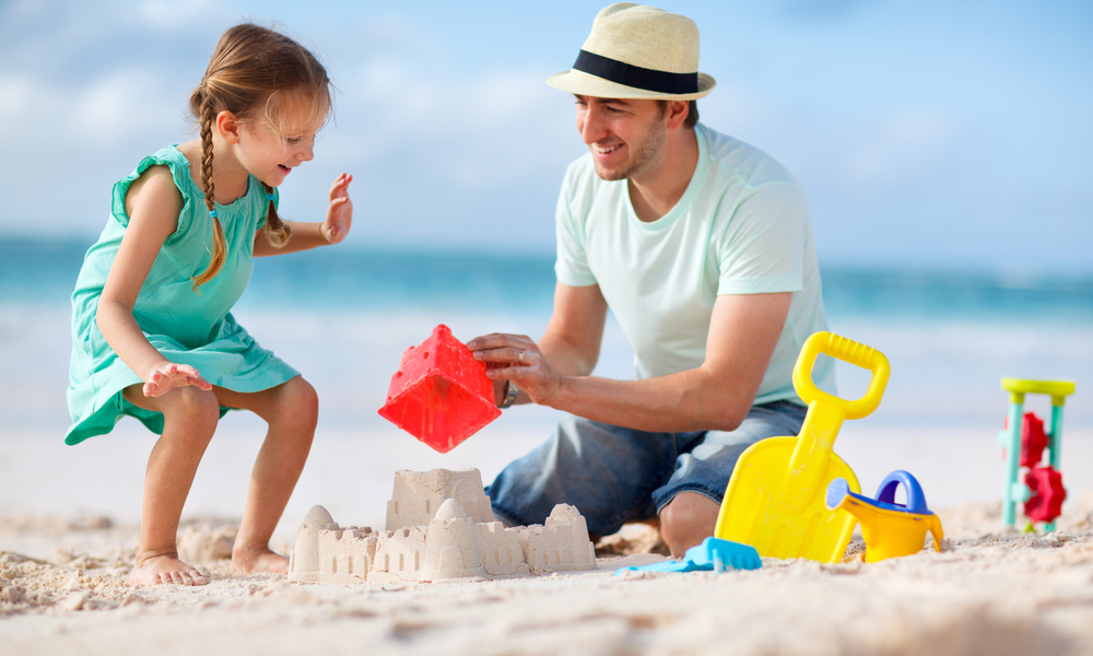 father and child playing on beach