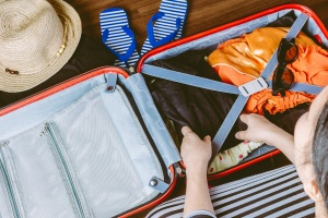 Woman packing a luggage on wooden floor