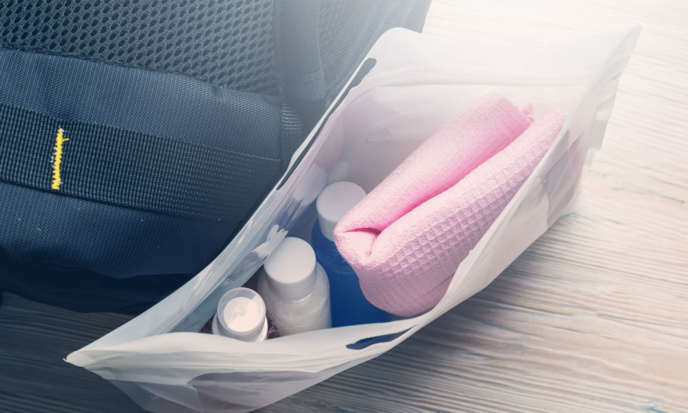 Set of travel bottles and towel in plastic bag