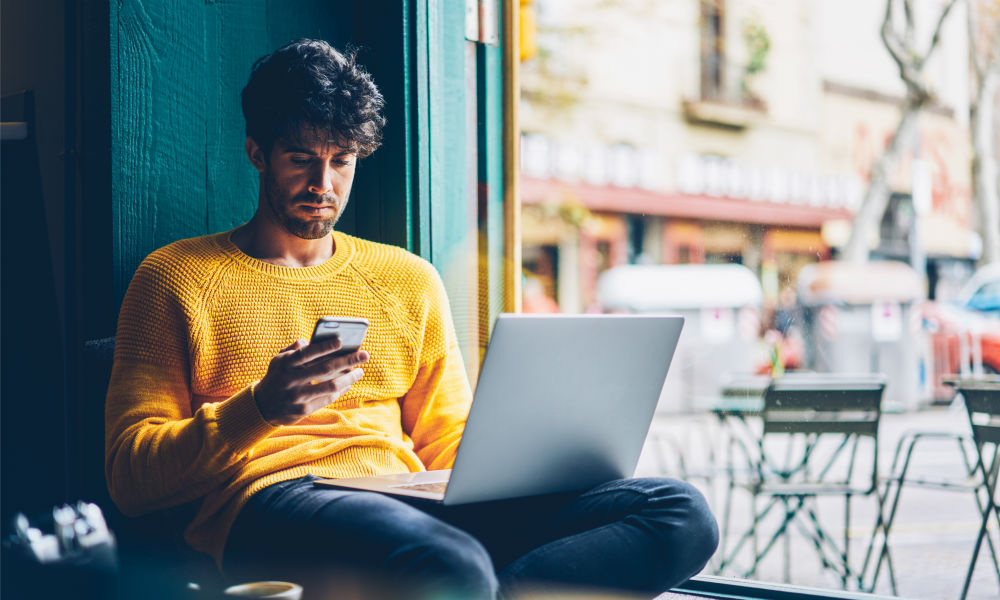 Hipster guy checking message on cellular during studying at netbook