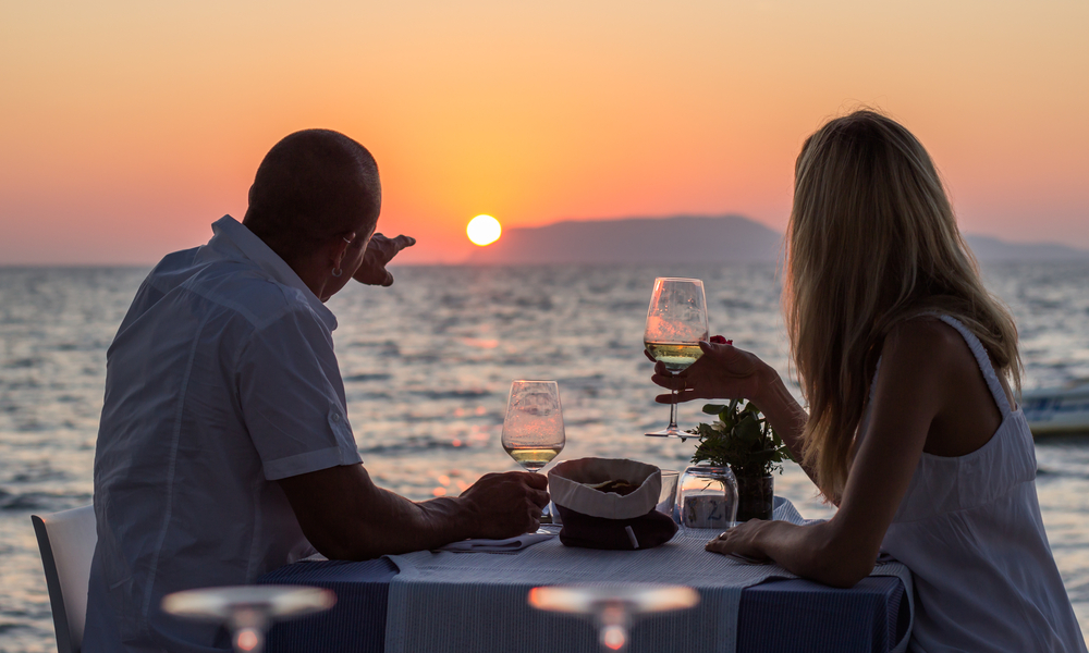 Couple drinking wine at sea beach restaurant at sunset