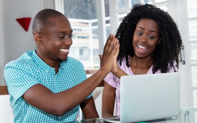 African american couple making online reservation with laptop at desk at home