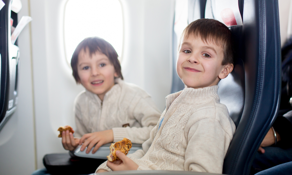 Two children, eating sandwiches on board in aricraft