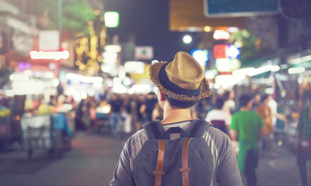 Young Asian traveling backpacker in Khaosan Road night market in evening in Bangkok, Thailand