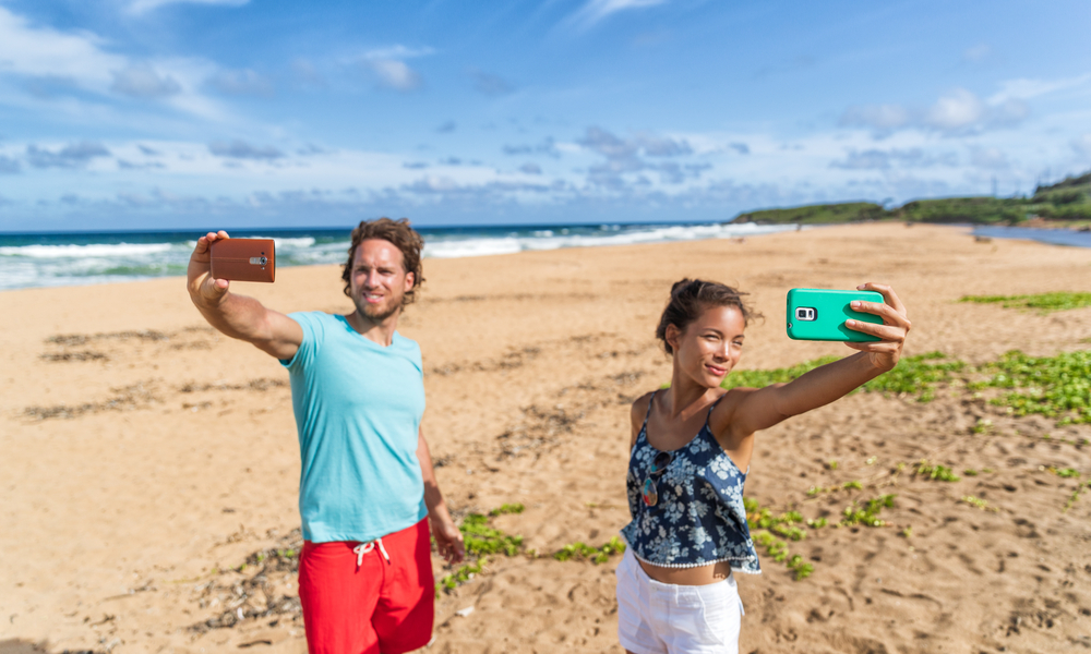 Self absorbed young people taking selfie pictures of themselves on beach vacation