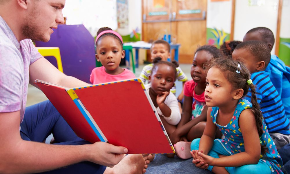 Volunteer teacher reading to a class of preschool kids 