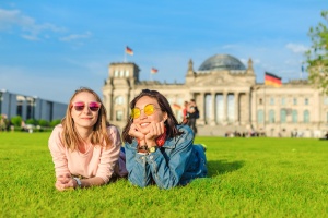 Two Young happy girls wearing sun glasses lying on a grass and have fun in front of the Bundestag building in Berlin