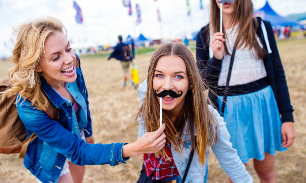 Teenage girls at summer festival with fake mustache